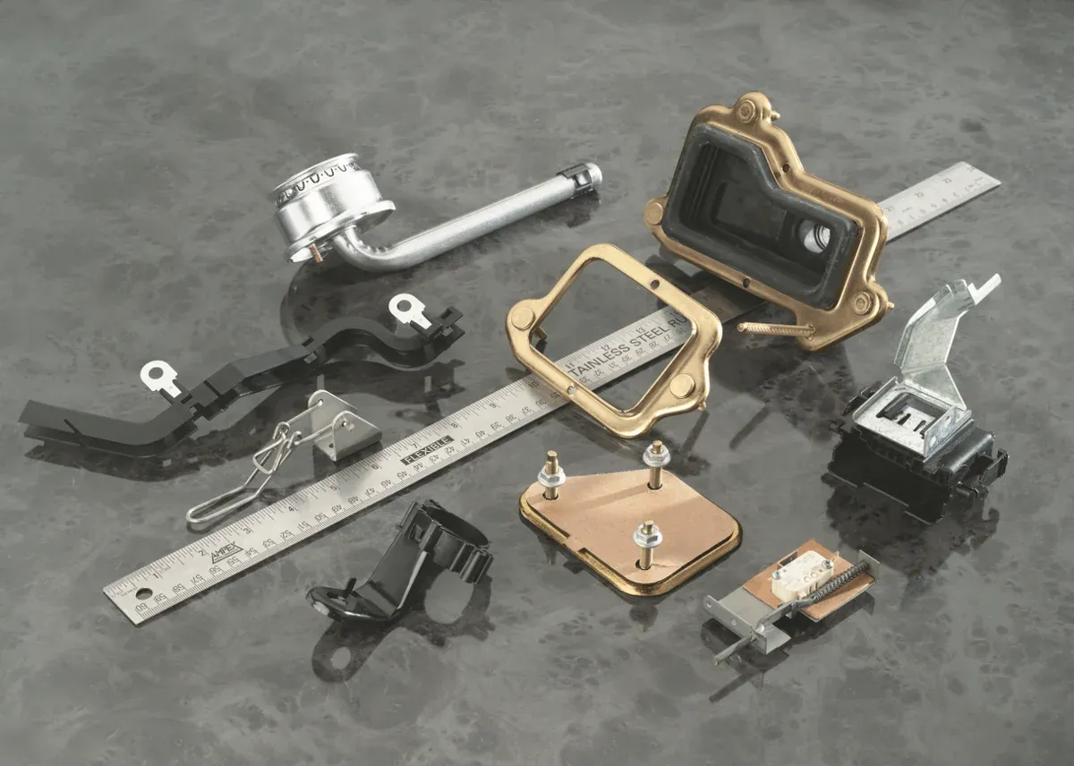 Formed brackets and stamped components shown beside a steel ruler